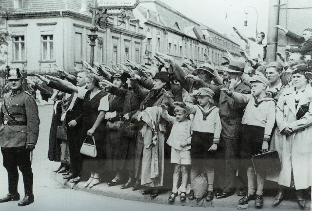 Berliners giving the German salute. Note the lady (extreme right of image) not holding her hand high nor looking all that impressed.